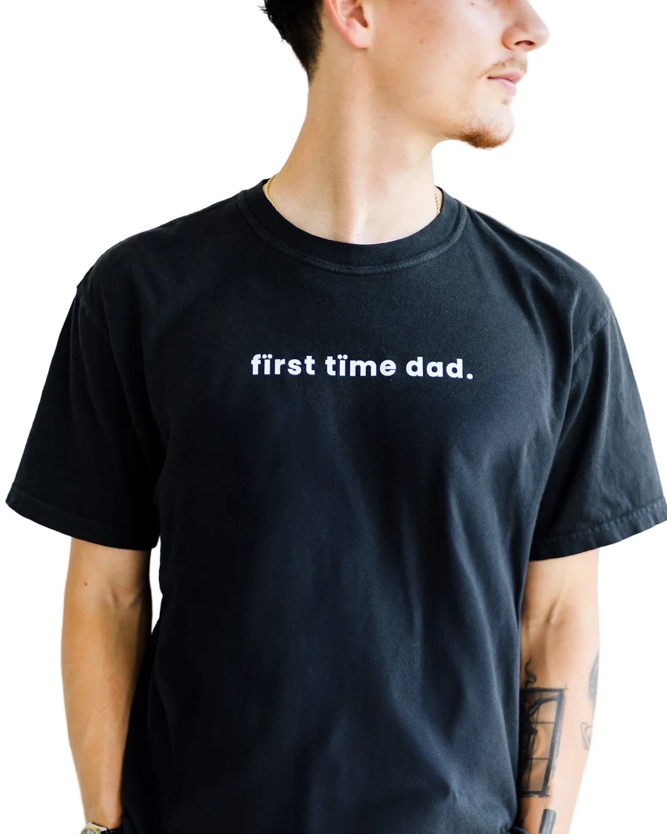 Person wearing a black t-shirt with 'first time dad.' text on a plain background