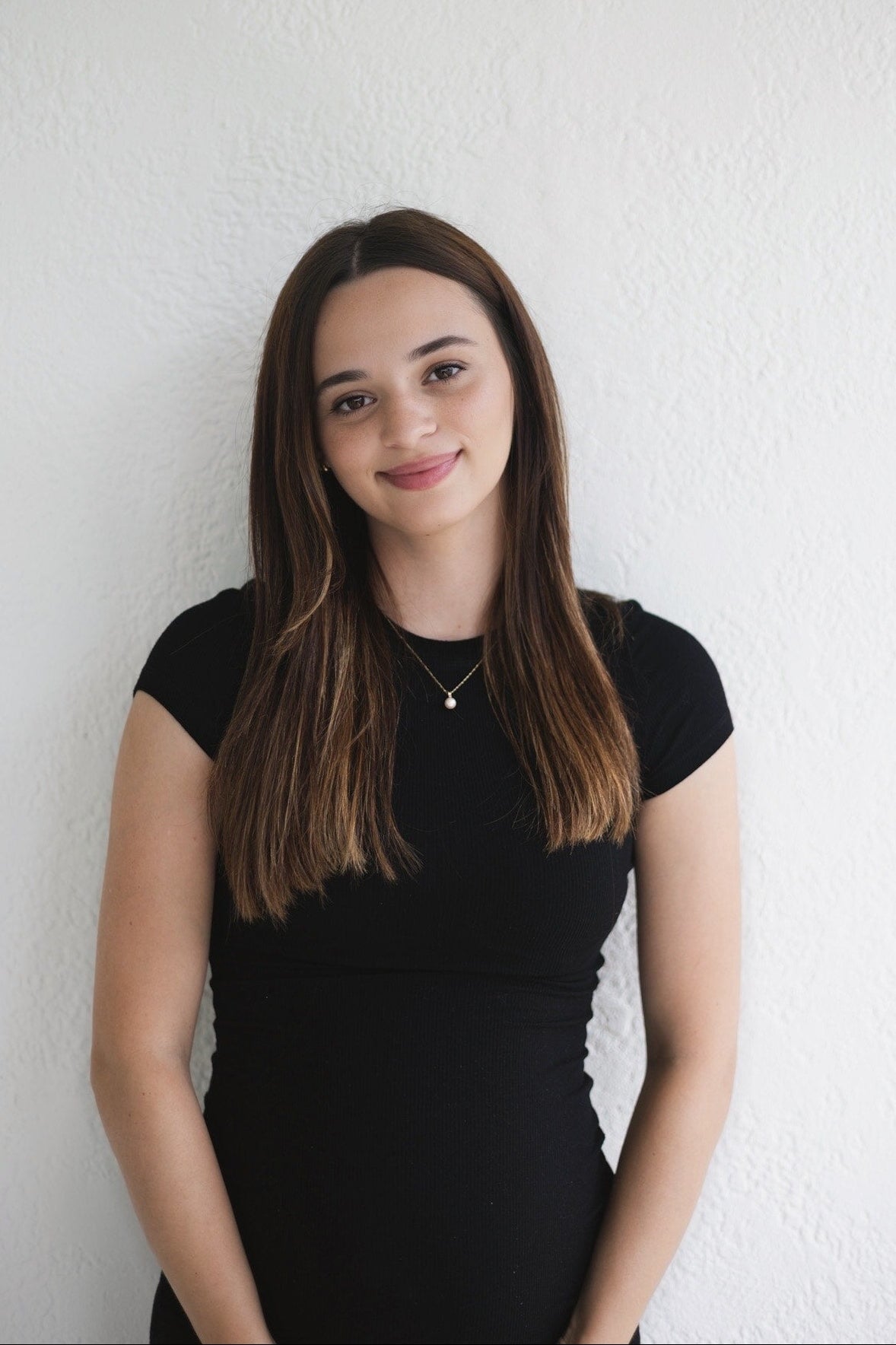 Woman wearing a black dress against a white wall