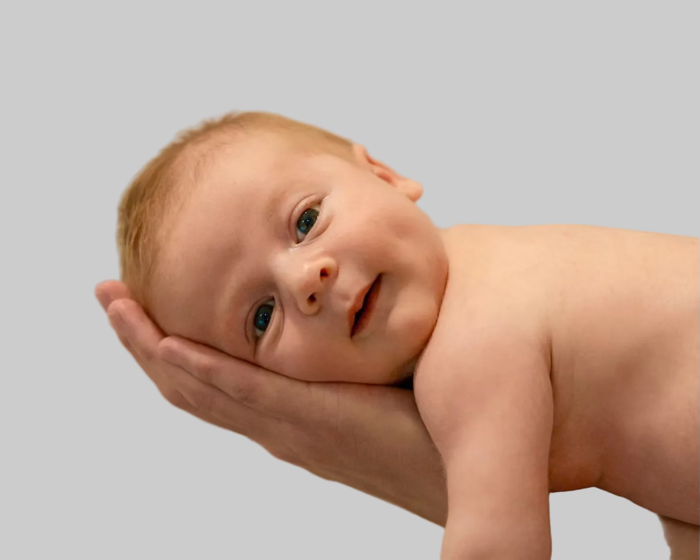 Newborn baby being held with a plain background
